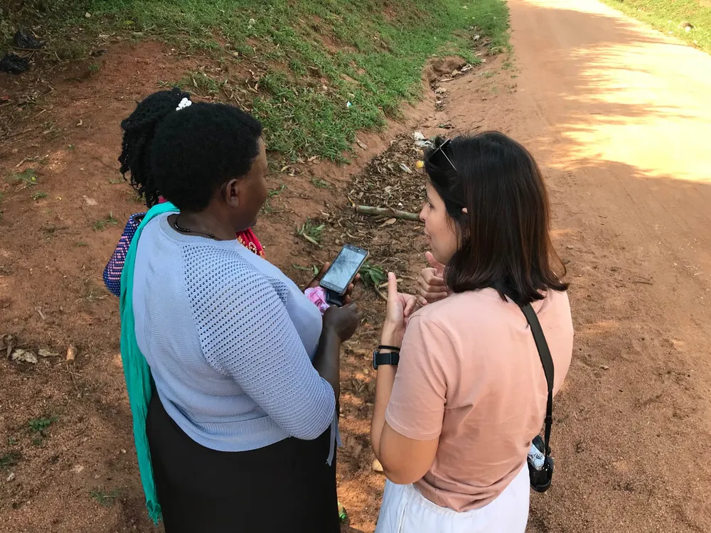 Reviewing the app with a community health worker outdoors in Uganda